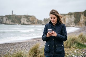 Jeune femme sur la plage de Normandie vérifiant ses offres d'emploi