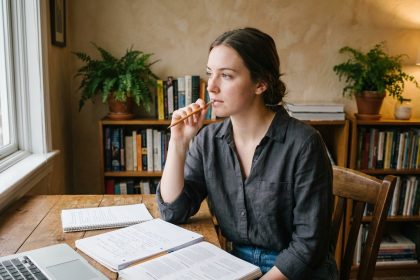 Jeune femme pensante en étude avec notebooks et ordinateur